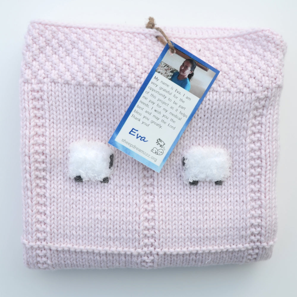Folded hand-knit baby blanket in pink.