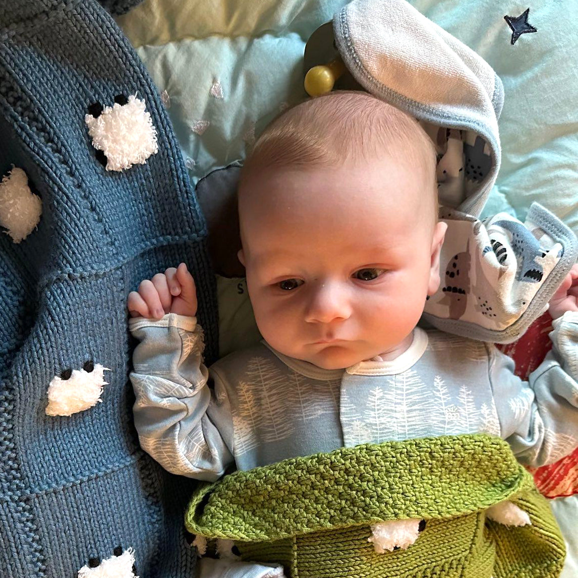 Young baby under a Cotton Elegance Sheep Dreamzzz baby blanket in the green color called Elms