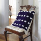 Mostly cotton navy blue baby blanket with cream border, laid out over a chair