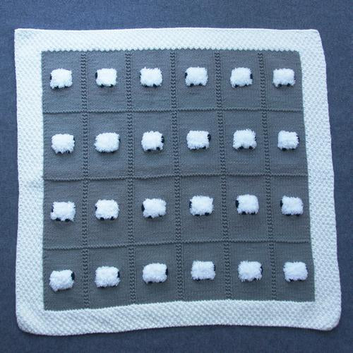 Dark gray baby blanket with white fluffy sheep. It has a white border.