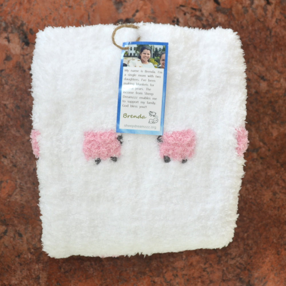 White fluffy sherpa baby blanket with pink sheep.