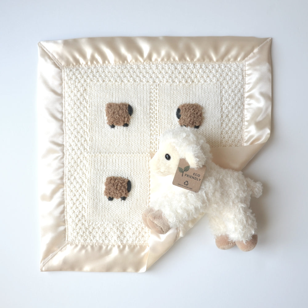Vanilla-colored lovey blanket with coffee-colored sheep and a fluffy sheep doll.