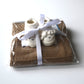 Newborn baby booties packaged with a blanket, tied on top beneath a satin ribbon.