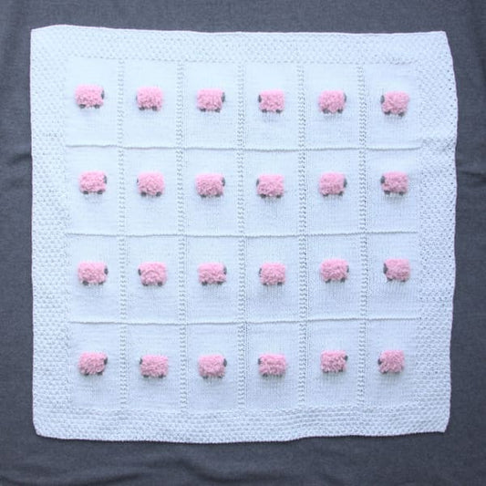 Mostly cotton hand-knitted baby blanket with 24 fluffy pink sheep. The color of the blanket is white.