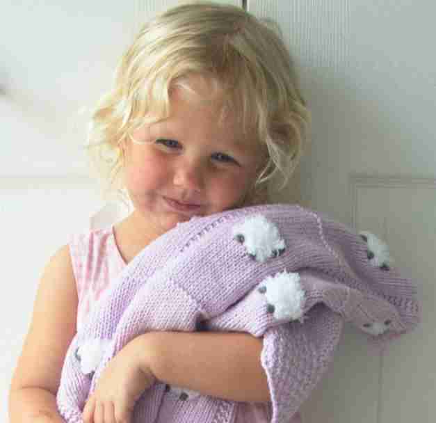 Little girl hugging a light lavender baby blanket.