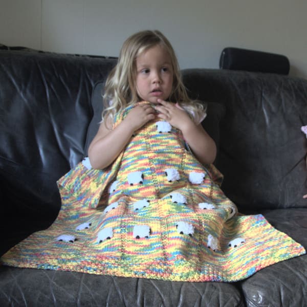 Young girl with a baby blanket called toybox because it has all  the colors in a box of Lego pieces