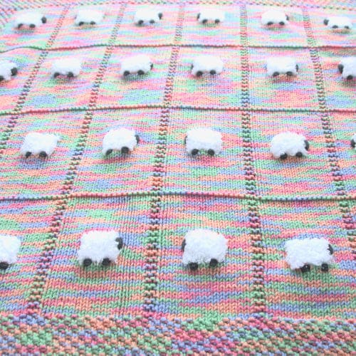 Close-up of Tutti-Frutti handmade baby blanket with fluffy white sheep.