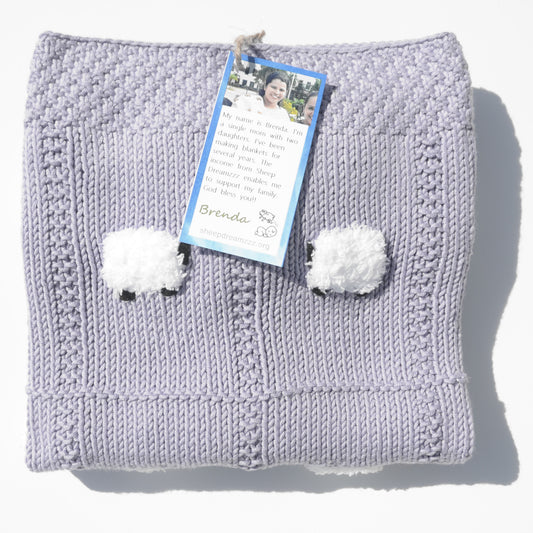 Lavender lightweight elegant baby blanket, handmade, folded, with 2 of the 24 fluffy white sheep showing.