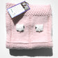 Light pink hand-knitted baby blanket, folded so two of the twenty-four fluffy sheep are visible.