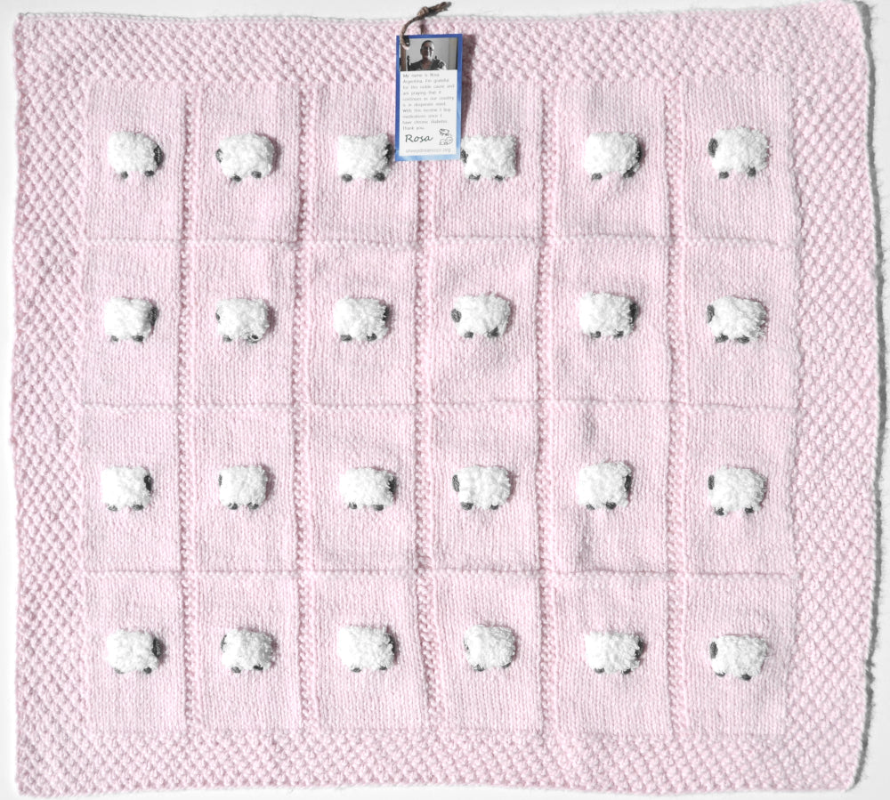 Pale pink blanket laid flat with 24 sheep on it.