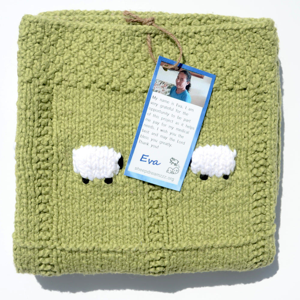Green organic cotton baby blanket, folded, with two white sheep showing.