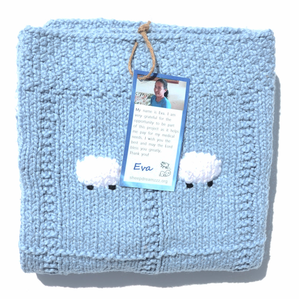 Lighter blue organic blanket, folded, with two organic white sheep showing.