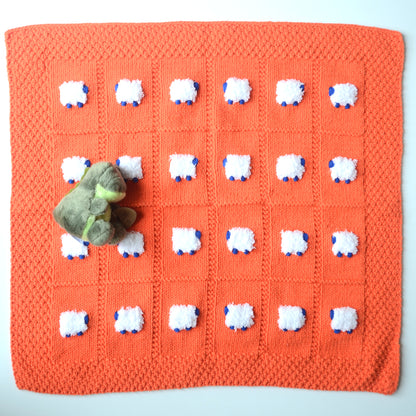 Orange blanket with white fluffy sheep that have blue heads and feet. For your babygator UF little one.