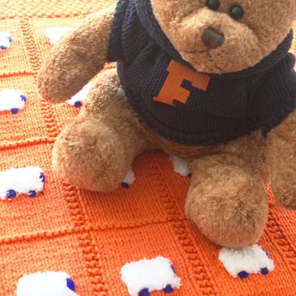 BabyGator UF Blanket - solid orange with white fluffy sheep that have blue faces and feet.